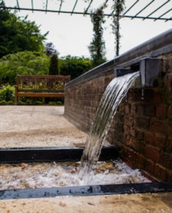 A contemporary waterfall flowing into a a rocky structure.